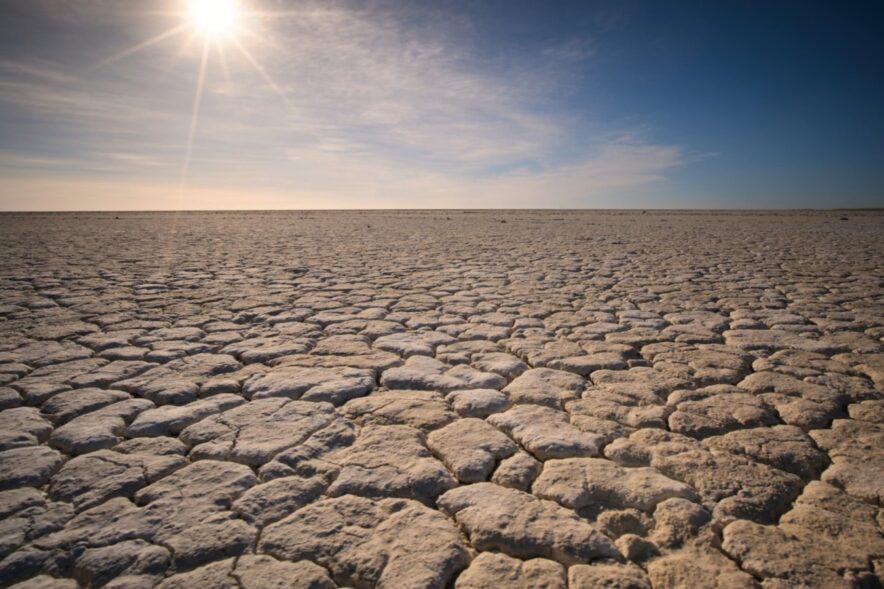 干ばつでひび割れた乾いた大地と照りつける太陽（気候危機のイメージ）